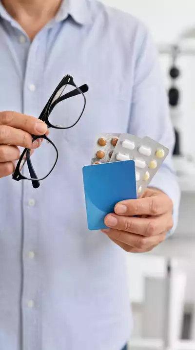 Person holding an insurance card, a list of medications, and glasses, ready for an eye exam